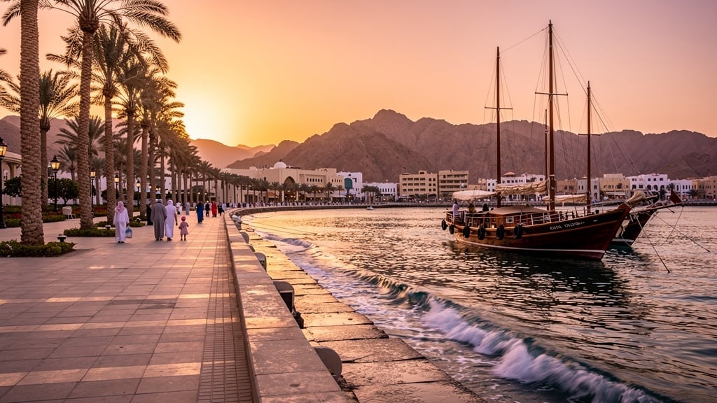 Muscat Corniche at sunset with traditional dhow boats on the Arabian Sea